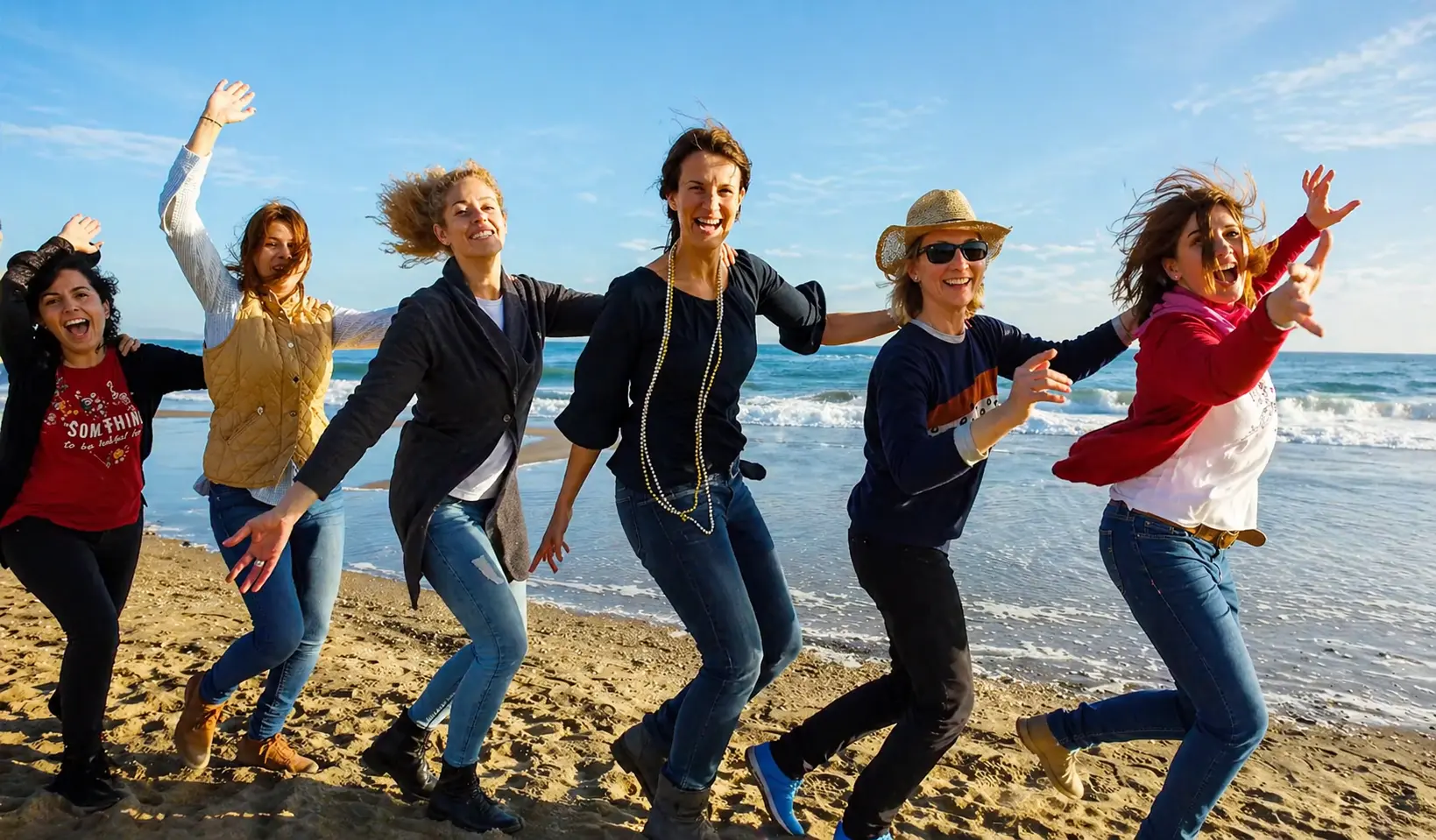 Grupo de amigas bailando en la playa durante una despedida en Barcelona