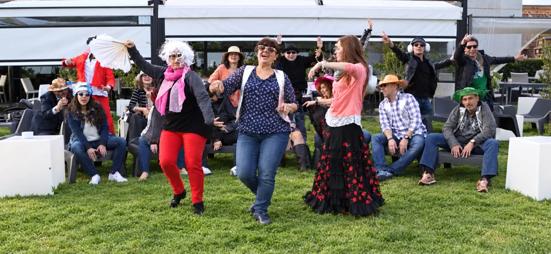 Invitados bailando con disfraces y accesorios en el jardín durante un videoclip de cumpleaños